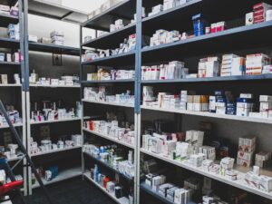 A hand places a prescription pill bottle in a closed, high dresser drawer near a digital thermometer.