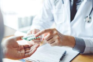 Pharmacist comparing a prescription label with two differently colored tablets on a counter.