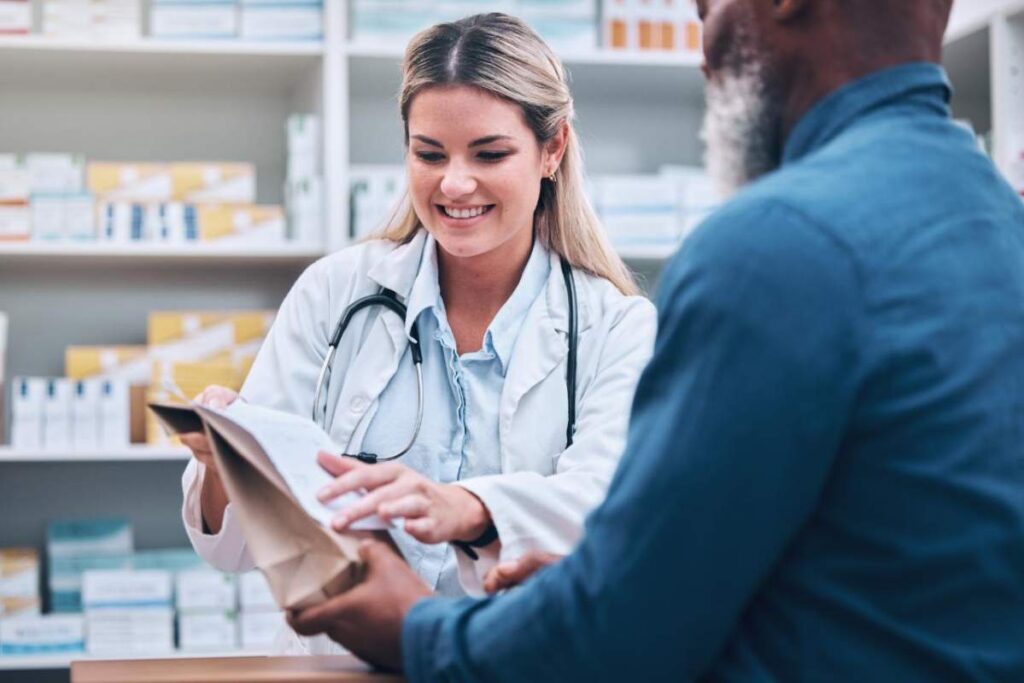 A person compares a medicine bottle lot number with a printed recall notice beside a phone.