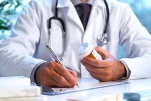 Pharmacist comparing two prescription bottles while explaining a medication change to an adult patient.